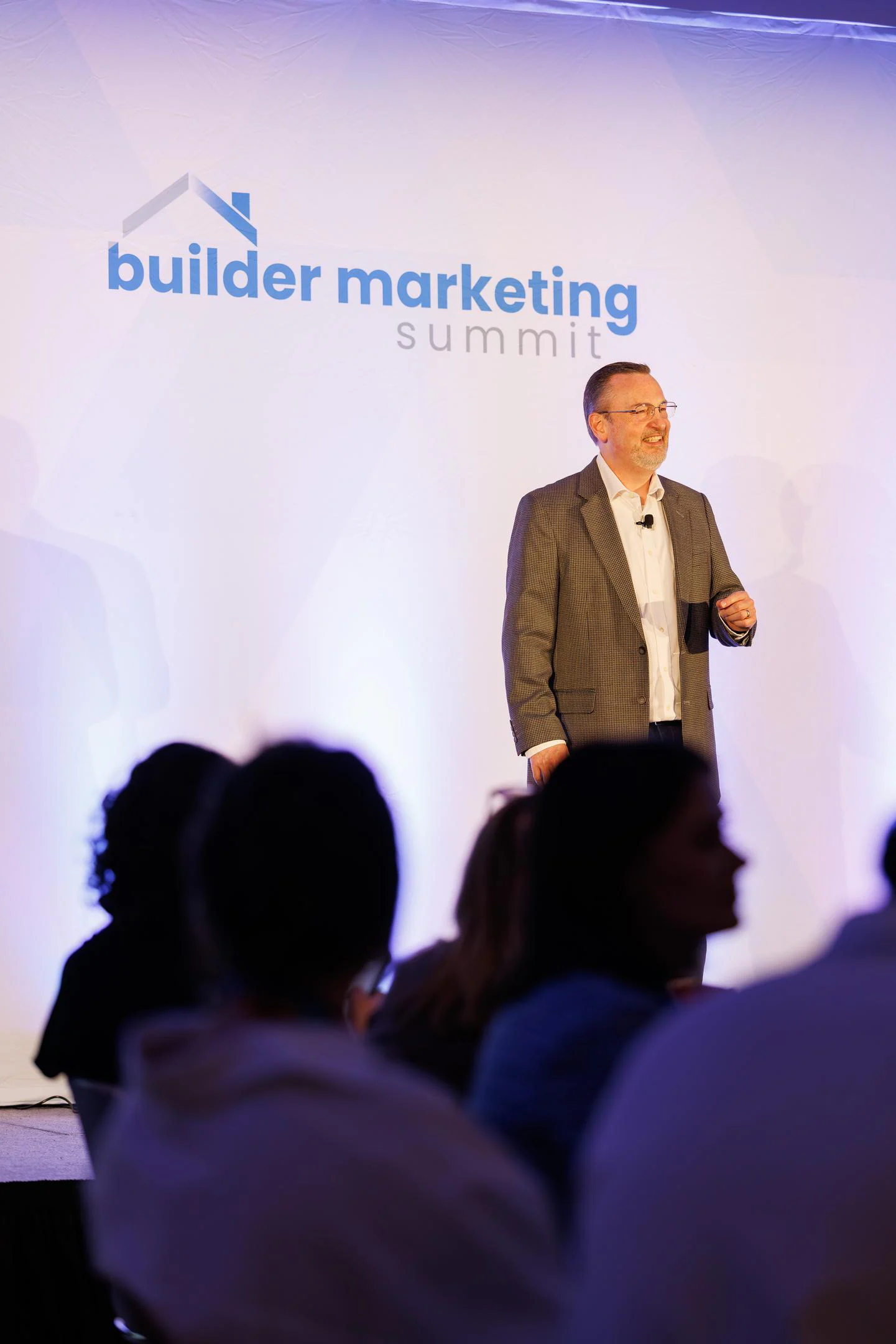 Greg Bray, President of Blue Tangerine, speaking on stage at the 2026 Builder Marketing Summit